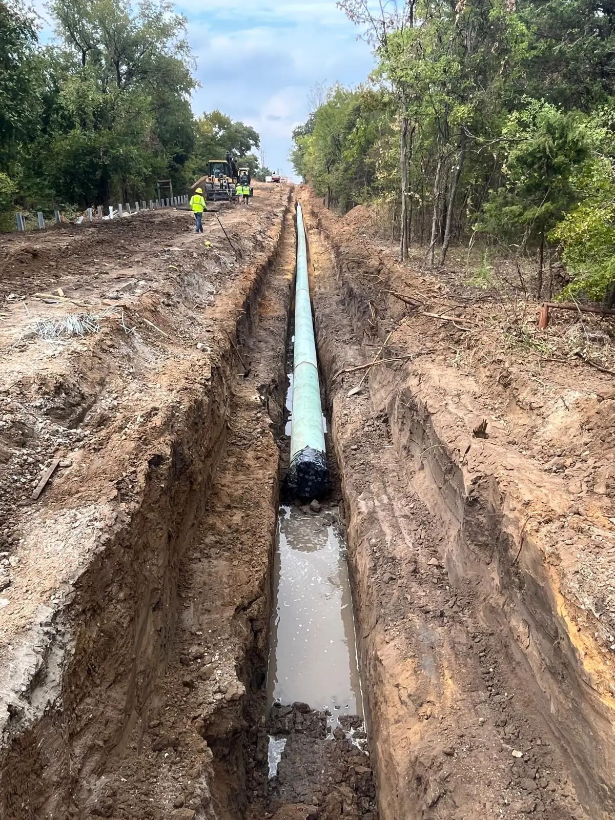 Large-diameter water transmission line strung along a wooded utility corridor in Texas
