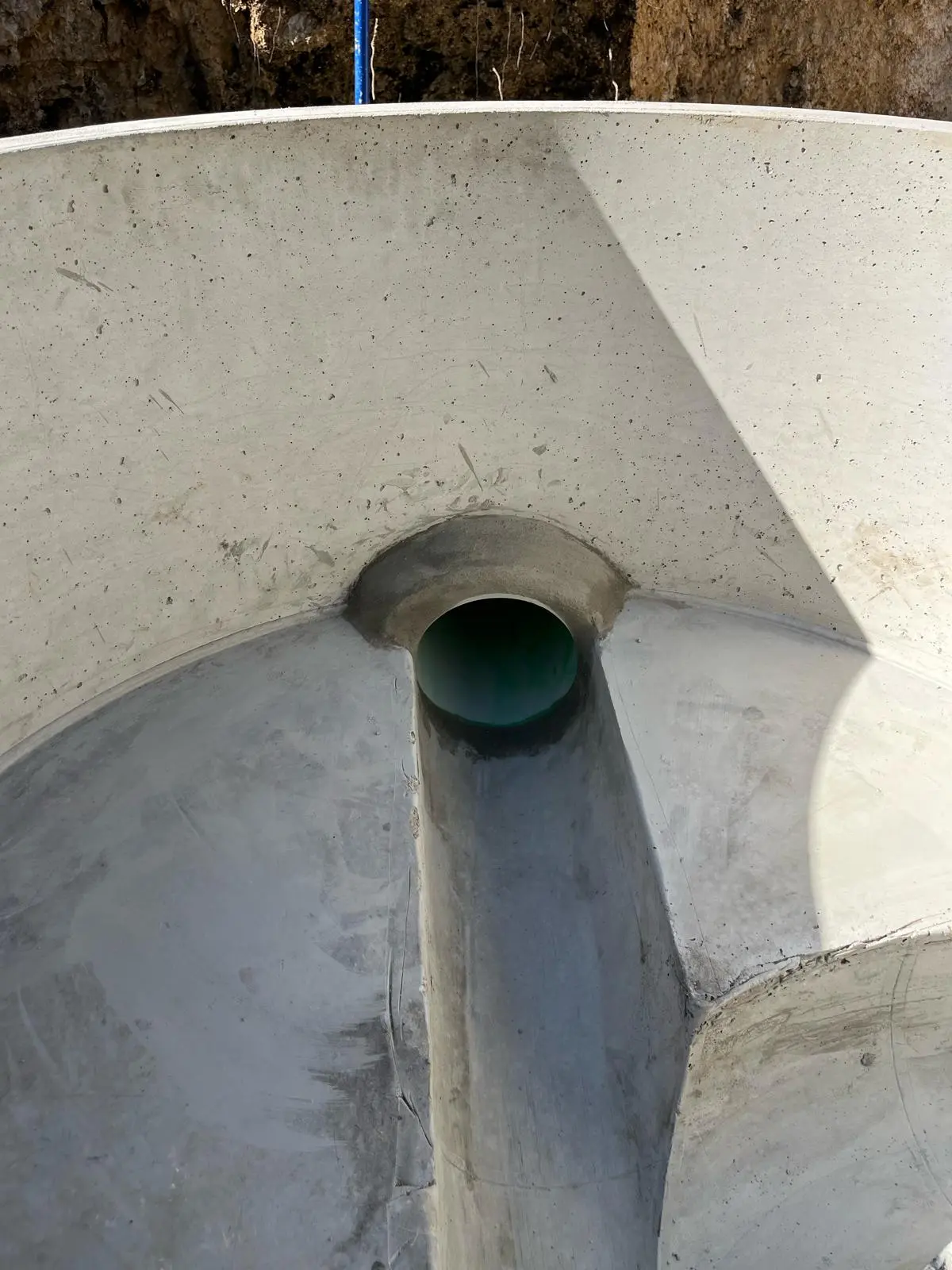 Channeled concrete invert with a PVC pipe running through a sanitary sewer manhole