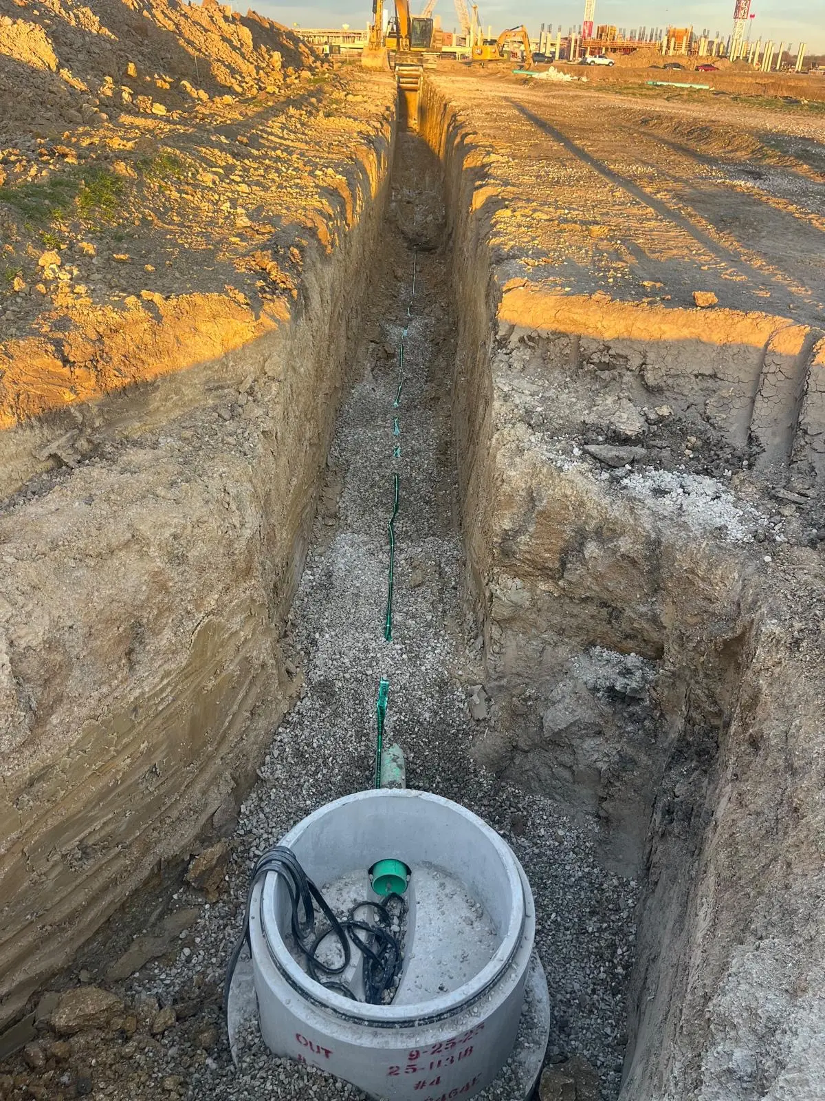 Sanitary sewer manhole base connected to a long trench at sunset