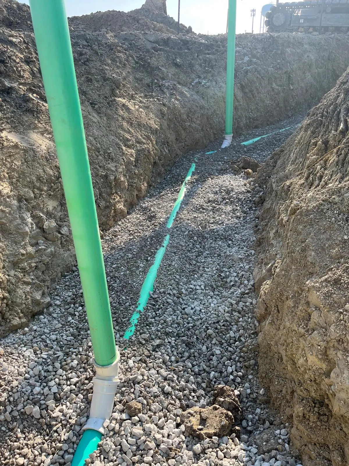Sanitary sewer service lines and cleanout risers in a rock-bedded trench