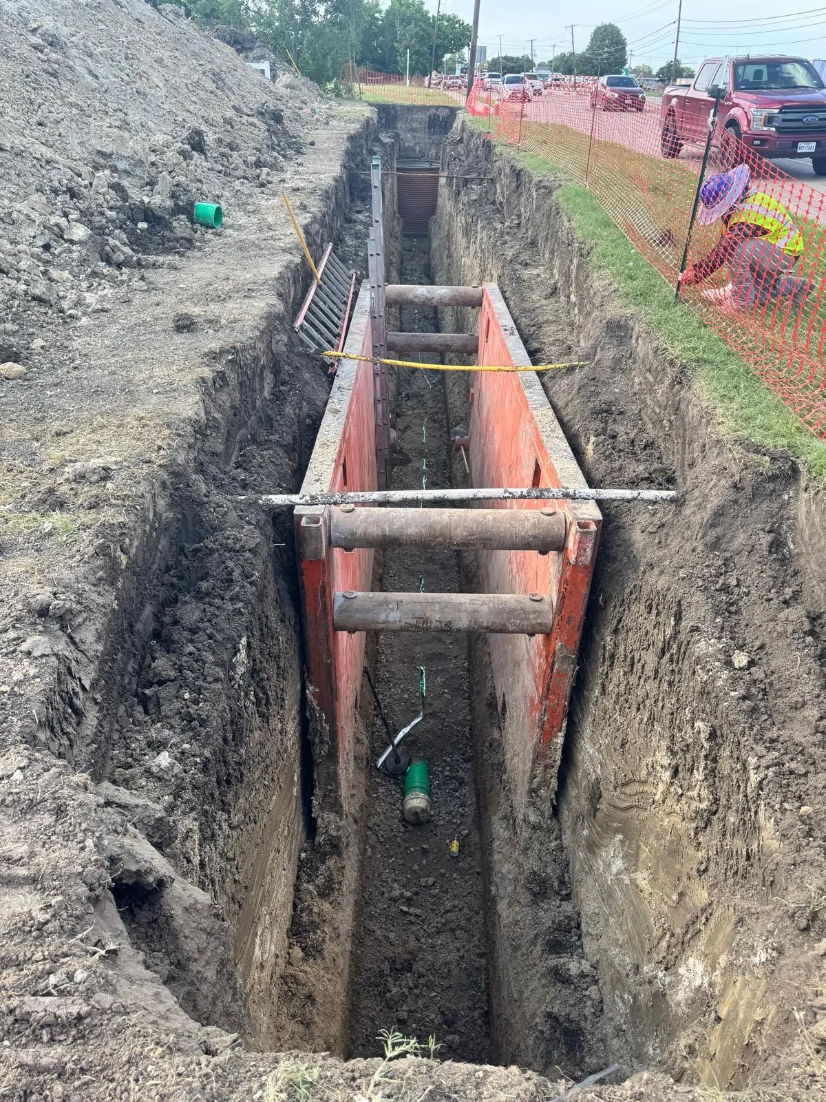 Trench shoring box protecting a crew during roadside utility work in DFW