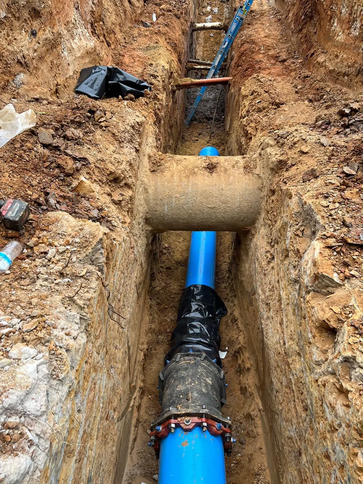 Water main restrained joint fitting and wrapped connection in a deep trench